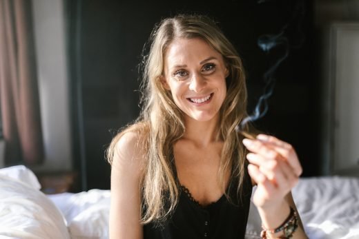 woman-in-black-tank-top-smiling-while-holding-a-cigarette